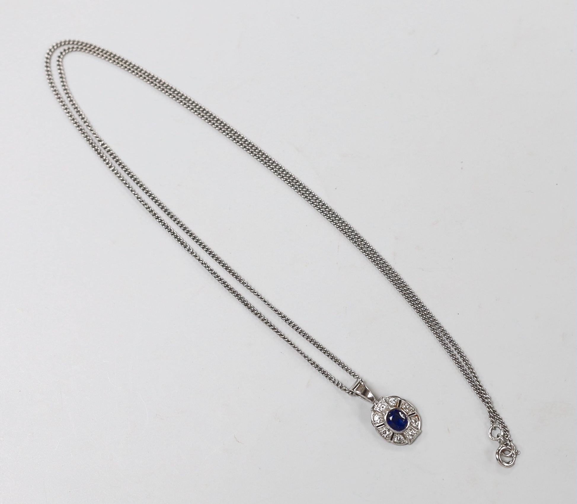 A modern 9ct white gold, sapphire and diamond set oval cluster pendant, 22mm, on a 9ct white gold chain, 60cm, gross weight 8.1 grams.
